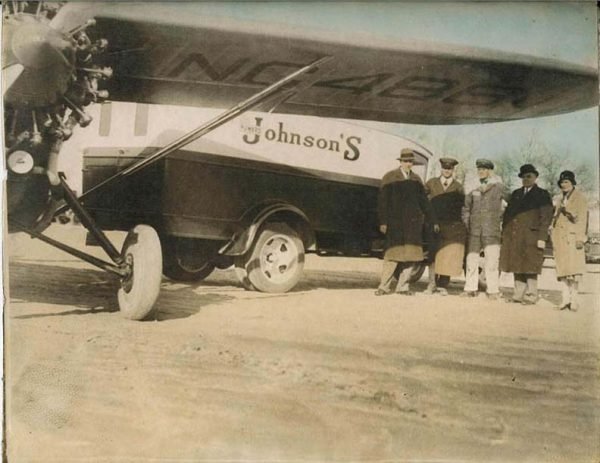 Howard D. Johnson stands (second from right) with one of his delivery trucks and planes.